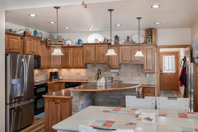 kitchen featuring tasteful backsplash, black appliances, and decorative light fixtures