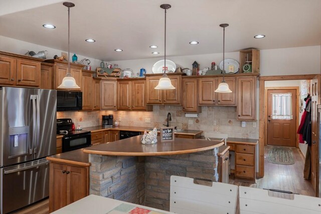 kitchen with hanging light fixtures, light hardwood / wood-style flooring, backsplash, a kitchen island, and black appliances