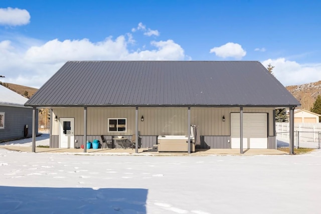 snow covered rear of property featuring an outbuilding and a garage