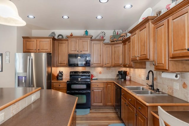 kitchen with tasteful backsplash, sink, black appliances, and light hardwood / wood-style floors