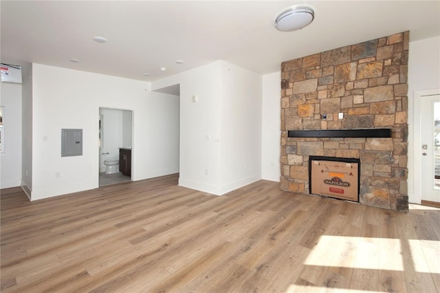 unfurnished living room with a stone fireplace and light wood-type flooring