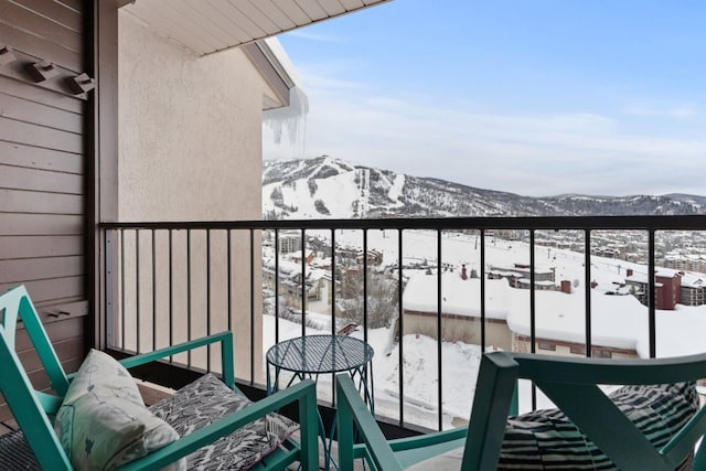 snow covered back of property featuring a mountain view