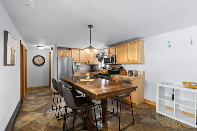 kitchen with light brown cabinetry, sink, pendant lighting, and appliances with stainless steel finishes