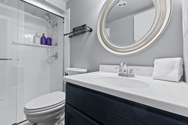 bathroom with vanity, toilet, and a shower with door