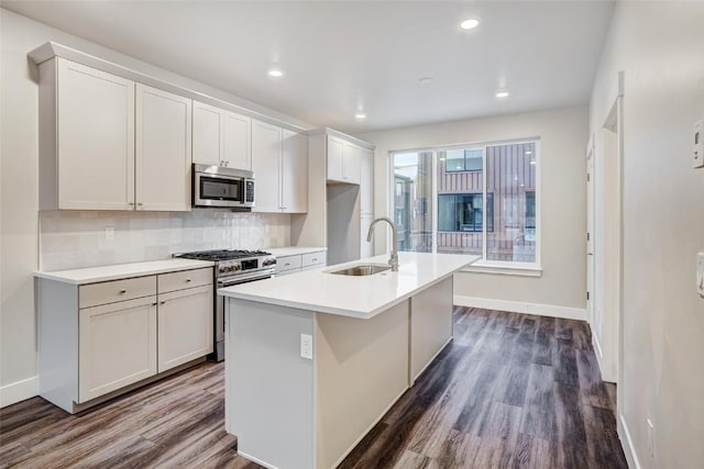 kitchen with stainless steel appliances, backsplash, dark wood-type flooring, a kitchen island with sink, and a sink