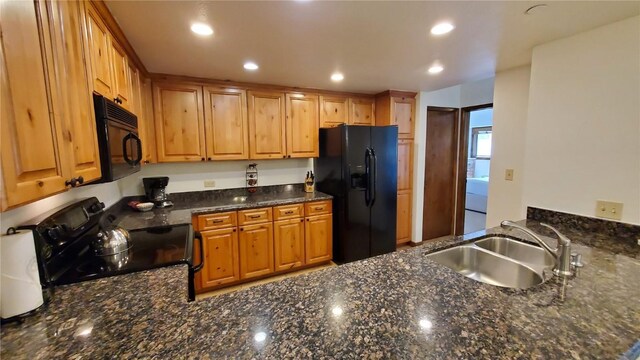 kitchen with dark stone counters, sink, and black appliances