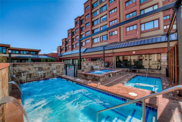 view of pool with a hot tub and pool water feature