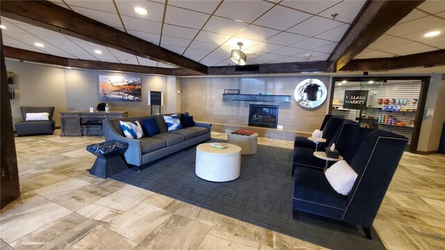 living room featuring beamed ceiling, a fireplace, and a drop ceiling