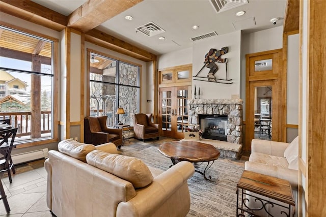 living room with beam ceiling, a stone fireplace, and baseboard heating