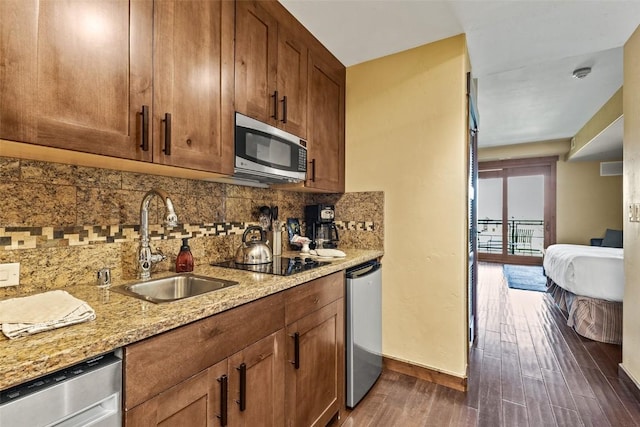 kitchen featuring stainless steel appliances, sink, backsplash, dark hardwood / wood-style floors, and light stone counters