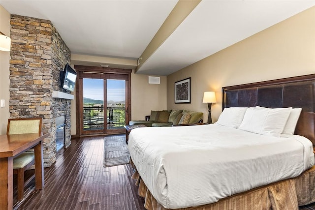 bedroom with dark wood-type flooring, access to outside, and a fireplace