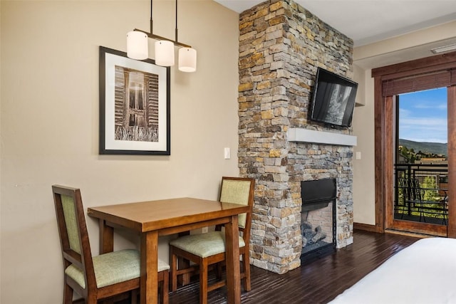 dining room with dark hardwood / wood-style flooring and a stone fireplace