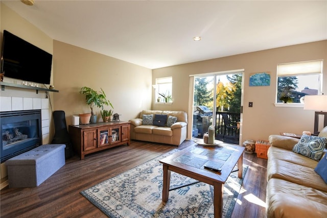 living room featuring dark wood-type flooring and a tiled fireplace