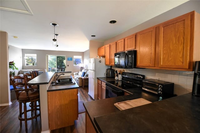 kitchen with a kitchen breakfast bar, dark wood-type flooring, sink, black appliances, and a center island