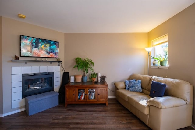 living room with dark wood-type flooring and a tiled fireplace