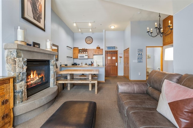 living room with track lighting, a fireplace, a chandelier, and carpet