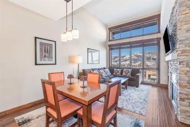 dining area featuring hardwood / wood-style flooring, a fireplace, and a high ceiling