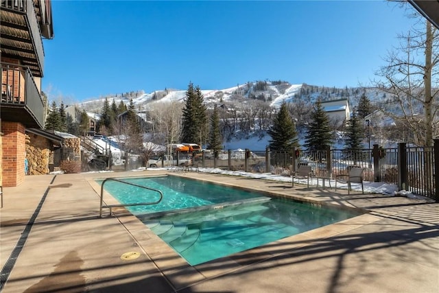 snow covered pool with a mountain view and a patio