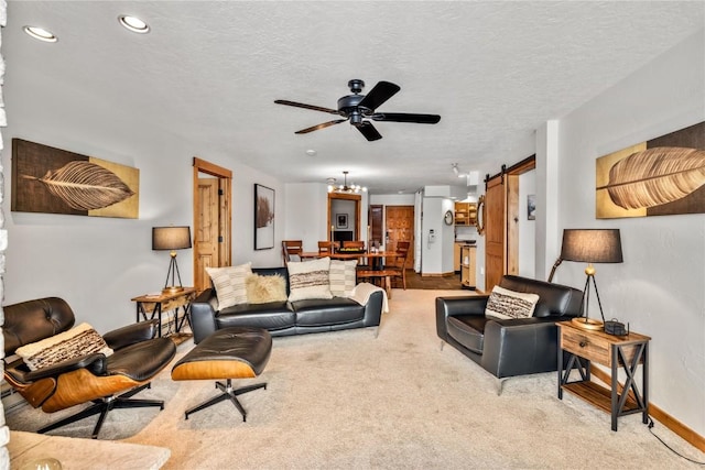 carpeted living room with ceiling fan, a barn door, and a textured ceiling