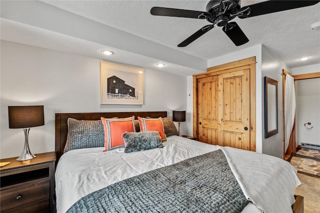 bedroom with ceiling fan, carpet floors, a textured ceiling, and baseboard heating