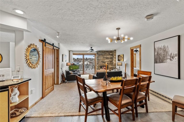 dining area featuring baseboard heating, a barn door, and a textured ceiling