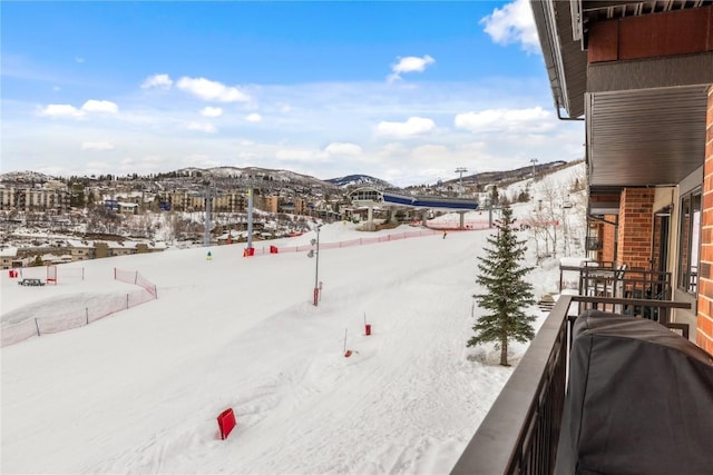 snowy yard with a balcony and a mountain view