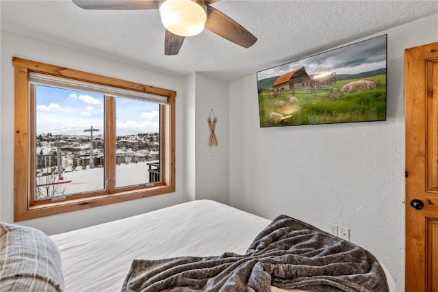 bedroom with ceiling fan and a textured ceiling