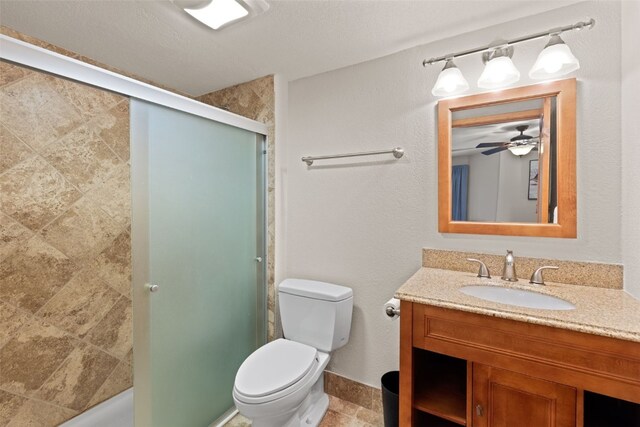 bathroom featuring vanity, toilet, ceiling fan, and a shower with shower door