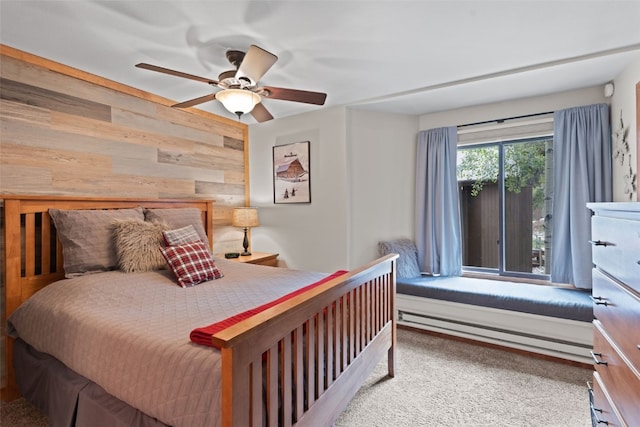 carpeted bedroom with ceiling fan, wood walls, and baseboard heating