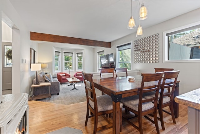 dining room featuring beam ceiling and light wood-type flooring