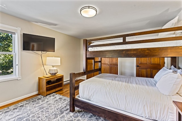 bedroom featuring baseboard heating and hardwood / wood-style flooring