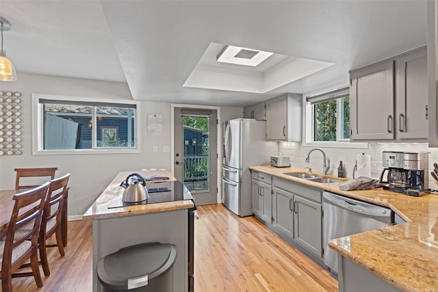 kitchen with backsplash, gray cabinetry, stainless steel appliances, sink, and pendant lighting