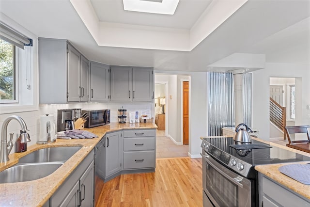 kitchen with stainless steel appliances, a raised ceiling, tasteful backsplash, and sink