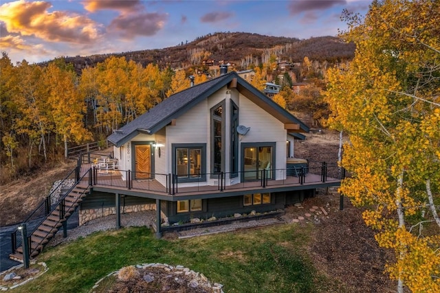 back house at dusk with a deck with mountain view and a yard