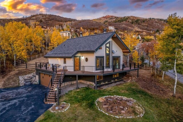 back house at dusk with a deck with mountain view and a garage