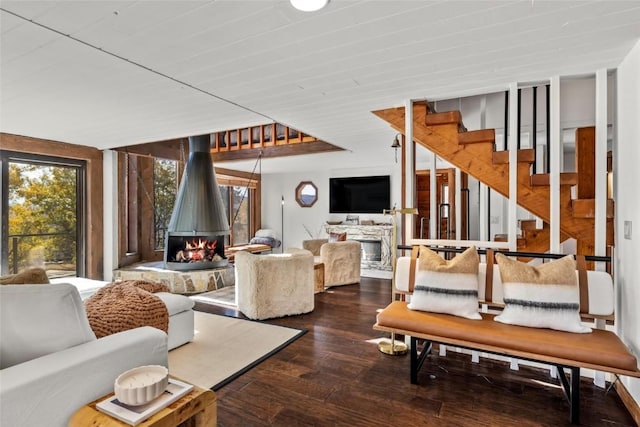 living room with dark hardwood / wood-style floors and a stone fireplace