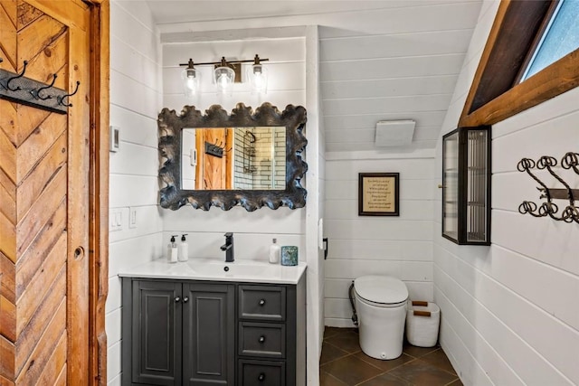 bathroom with vanity, lofted ceiling, tile patterned floors, wooden walls, and toilet