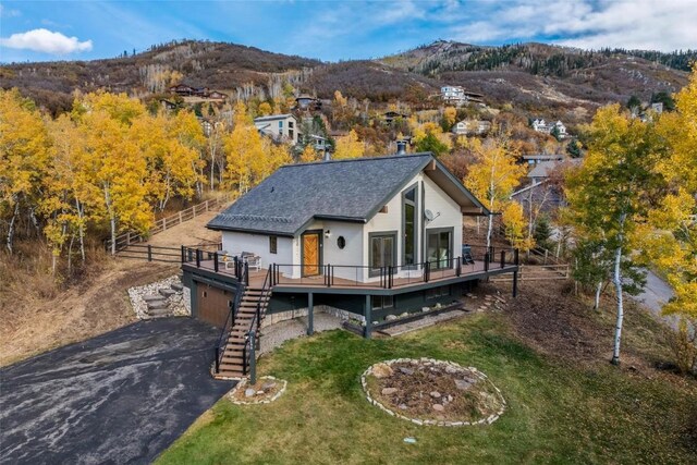 back of property featuring a deck with mountain view and a yard