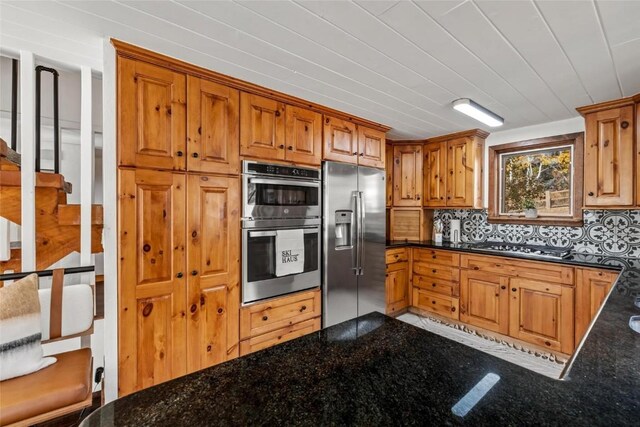 kitchen with dark stone countertops, decorative backsplash, and appliances with stainless steel finishes