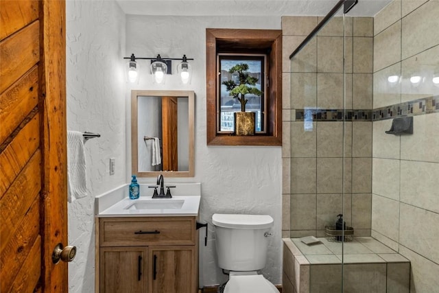 bathroom with toilet, vanity, and tiled shower