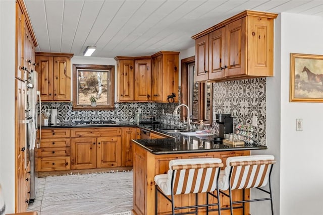 kitchen with sink, kitchen peninsula, dark stone countertops, a breakfast bar area, and wood ceiling