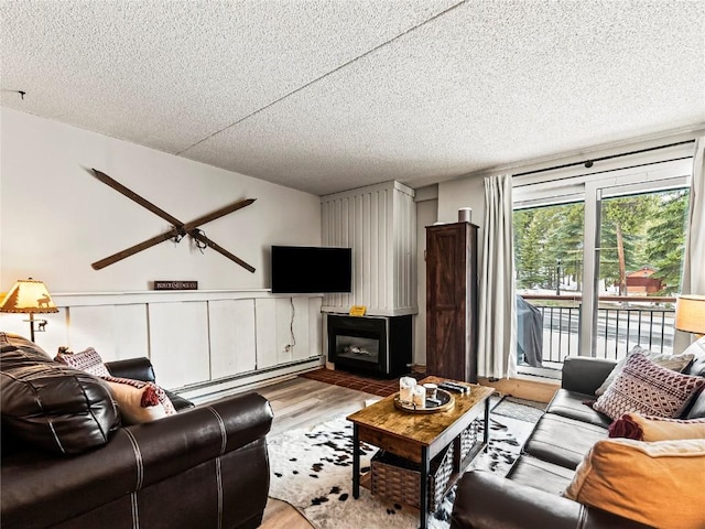 living room with ceiling fan, light hardwood / wood-style floors, a textured ceiling, and a baseboard heating unit