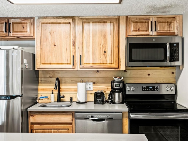 kitchen with a textured ceiling, sink, stainless steel appliances, and wooden walls