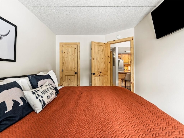 bedroom featuring stainless steel fridge and a textured ceiling