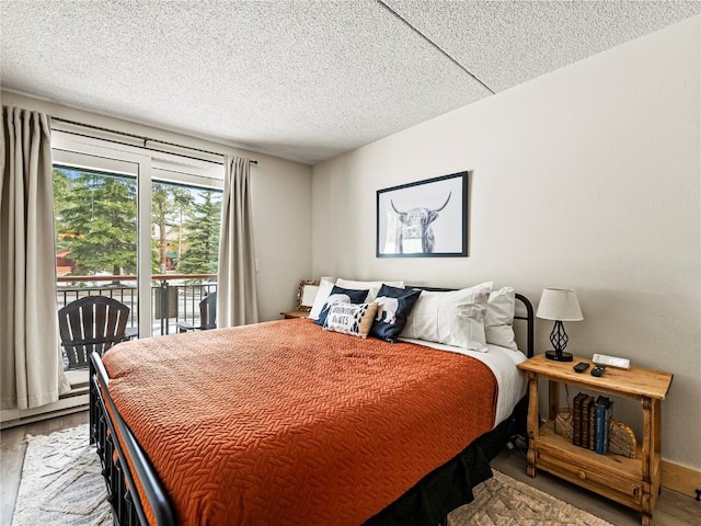 bedroom featuring hardwood / wood-style floors, access to exterior, and a textured ceiling