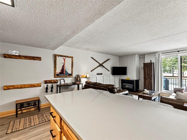 kitchen with a textured ceiling, light wood-type flooring, and a wood stove