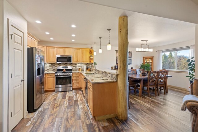 kitchen with kitchen peninsula, decorative backsplash, light stone countertops, stainless steel appliances, and pendant lighting