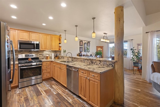 kitchen with kitchen peninsula, sink, hanging light fixtures, and appliances with stainless steel finishes