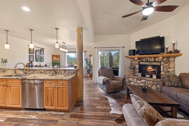 kitchen featuring a stone fireplace, sink, stainless steel dishwasher, decorative light fixtures, and light stone counters