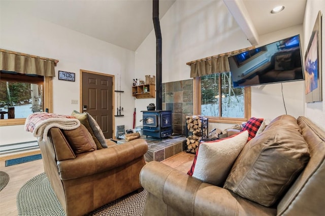 living room with a wood stove, high vaulted ceiling, a baseboard radiator, and light wood-type flooring